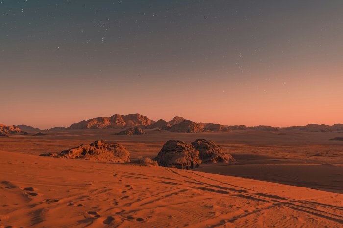 Desert landscape under a starry sky at sunset