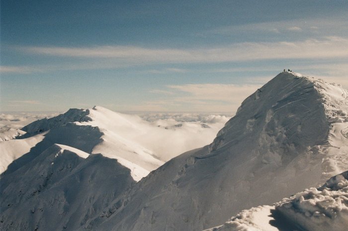 Snowy mountain peaks with tiny figures on summit