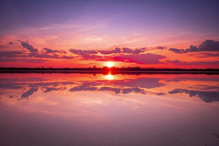 Sunset over a calm body of water with reflections