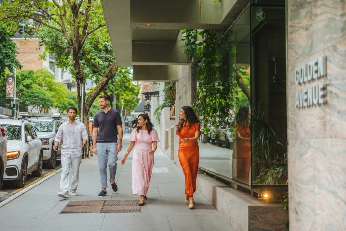 Four people walking on a city sidewalk