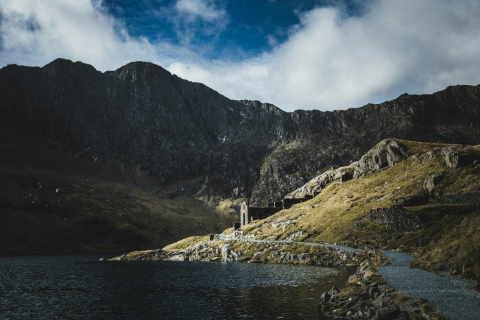 Ruined structure on a grassy mountainside by a lake