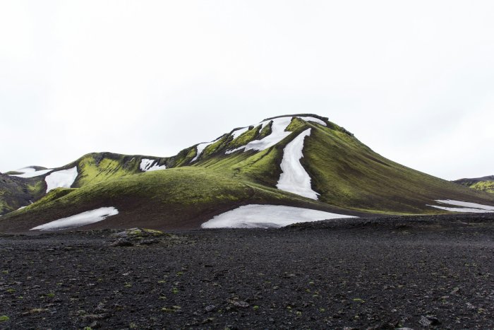 Mossy mountain with snow patches and dark ground