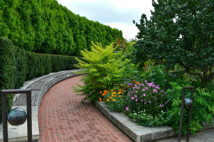 Curving brick path with lush garden and trees
