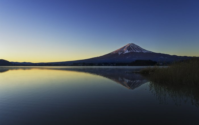 Mount Fuji reflected in a calm lake at dawn