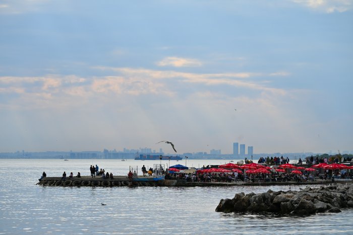 People enjoying a waterfront cafe with city skyline
