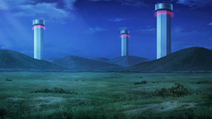Three tall towers in a grassy field at night