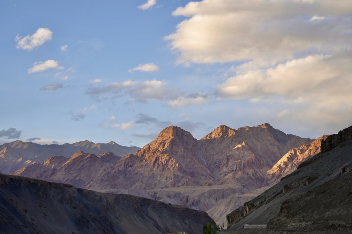 Sun-kissed mountain range under a cloudy sky