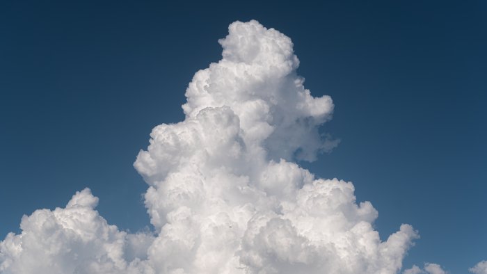 Cumulonimbus clouds with a distant airplane