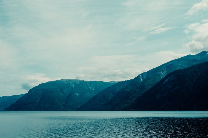 Serene Fjord with Majestic Mountains Under Cloudy Sky