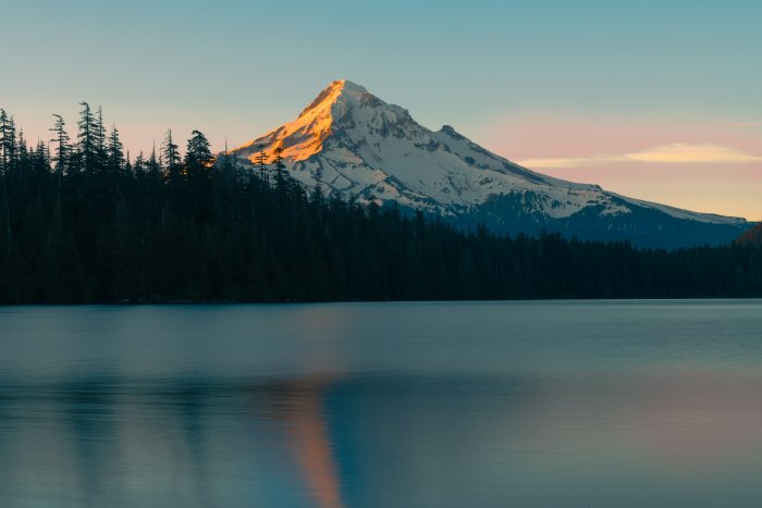 Snow-capped mountain reflected in a calm lake at sunset