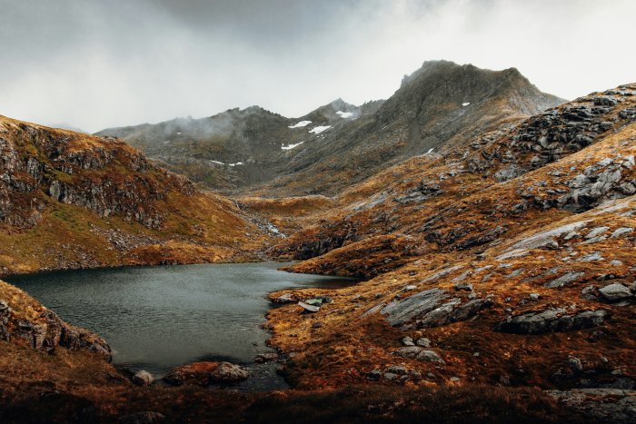 Mountain lake with rocky shores and overcast sky