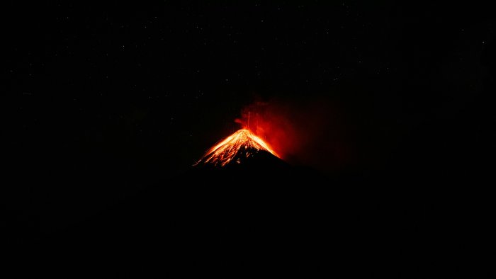 Volcano erupting at night with stars