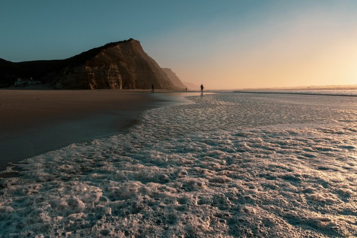 People walking on a beach at sunset