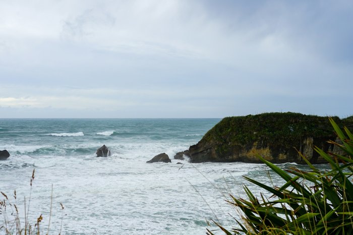 Rugged Coastline with Crashing Waves and Green Overgrowth