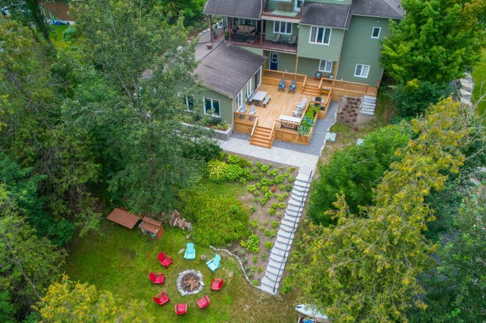Aerial view of a green house with a large wooden deck and backyard