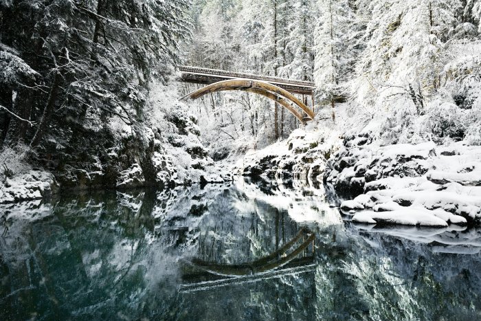 Snowy bridge over a river in a forest