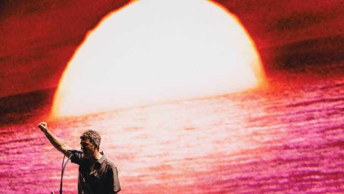 Noel Gallagher performs with a sunset backdrop