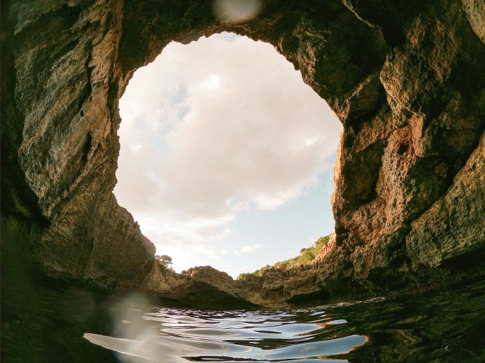 Cave opening to the sky over rippling water