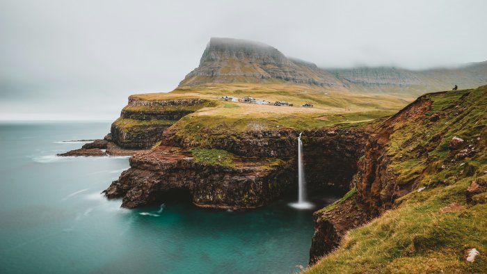 Waterfall cascading into the ocean from cliffs