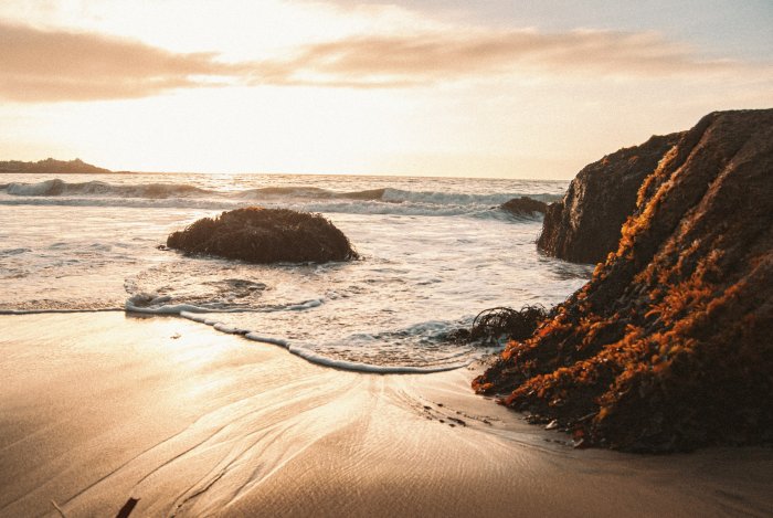 Ocean waves crashing on a rocky shore at sunset