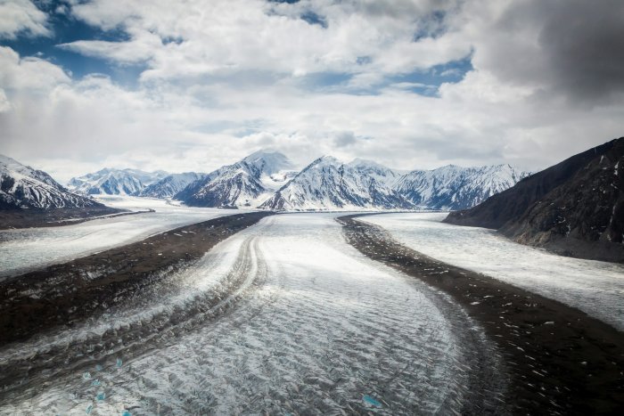 Glacier valley with snow-capped mountains under clouds
