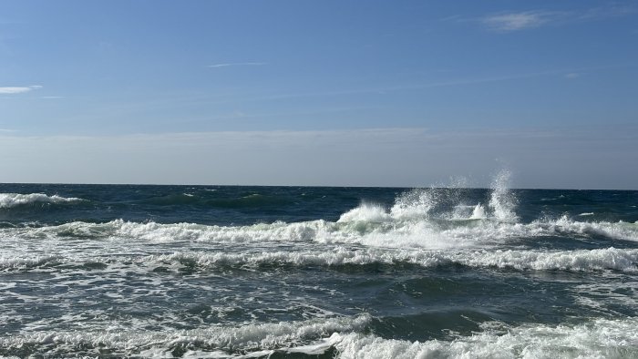 Ocean waves crashing under a clear blue sky