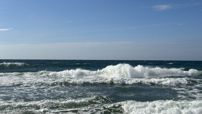 Ocean waves crashing under a clear blue sky