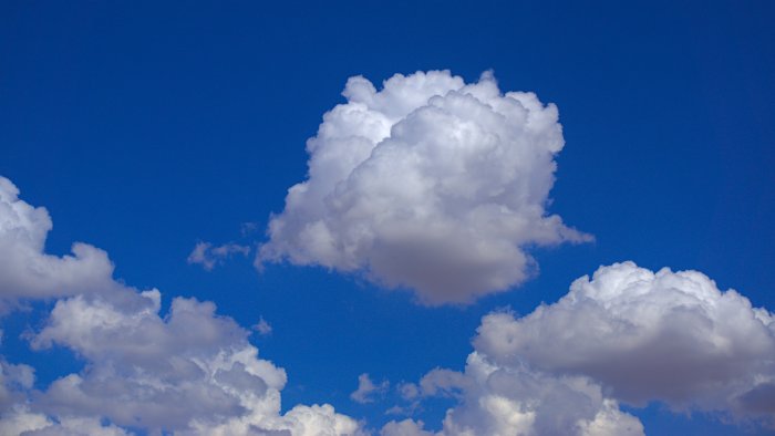 Fluffy white clouds against a bright blue sky