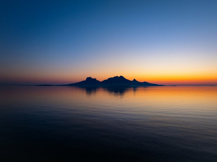 Islands silhouetted against a sunset over the ocean