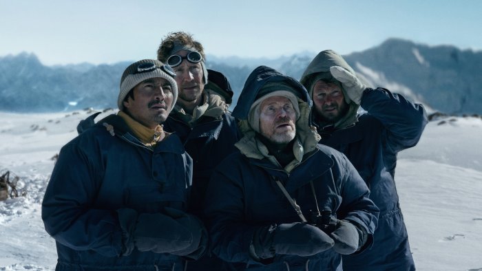 Four men in winter gear on a snowy mountain