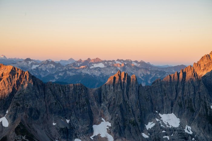 Jagged mountain range at sunrise with snow patches