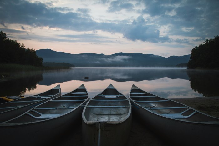 Canoes lined up on a misty lake at dawn