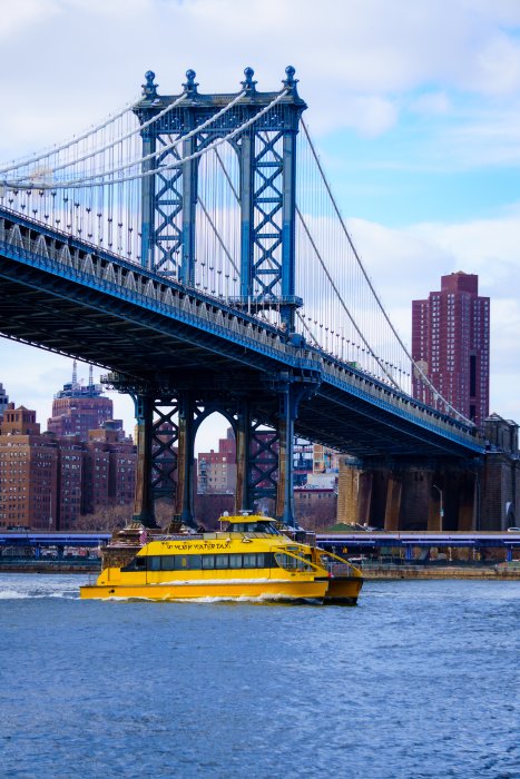 Yellow water taxi passes under the Manhattan Bridge