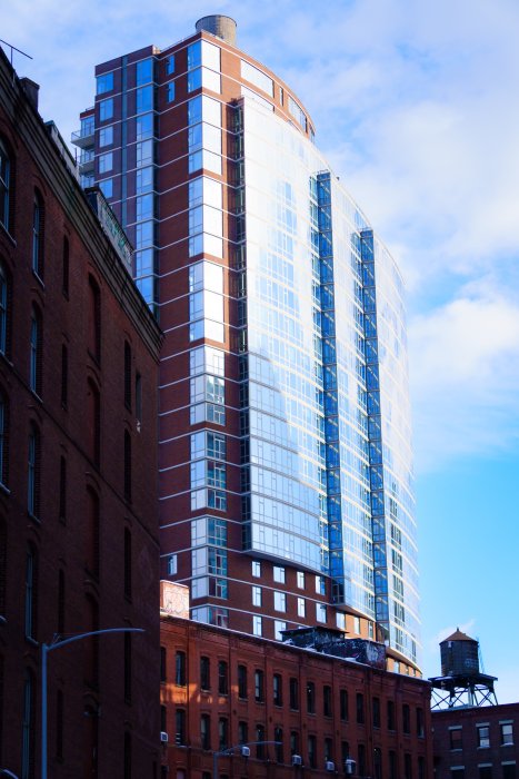 Modern glass skyscraper next to brick buildings