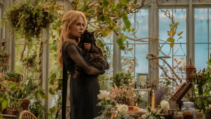 Nicole Kidman with a black cat in a greenhouse