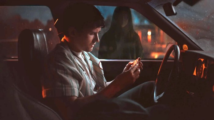 Man in car looking at coin, woman in background