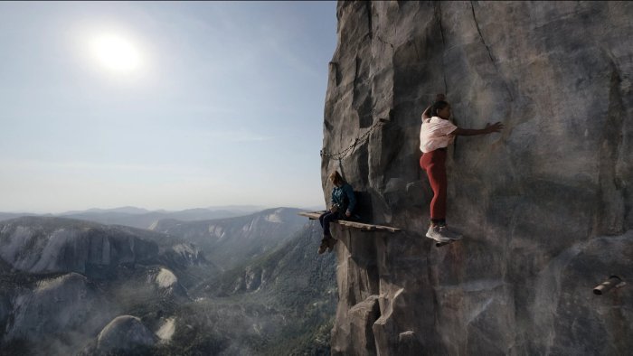 Two women climbing a sheer rock face