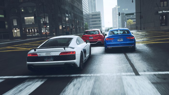 Three Audi cars driving on a wet city street