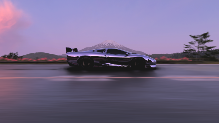 Chrome sports car driving on a road with mountains
