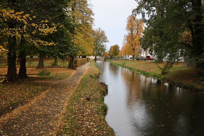 Autumn canal path with trees and a building