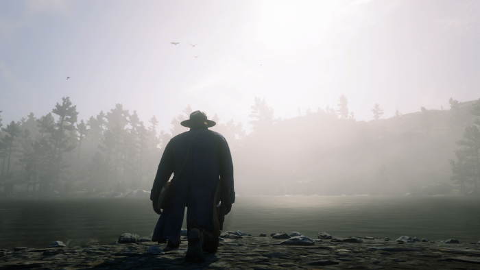 Man in hat and coat by a foggy lake