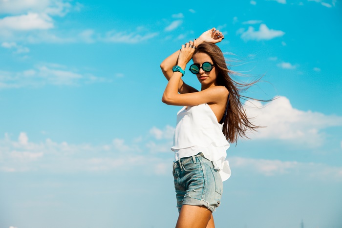 Woman with long hair wearing sunglasses and shorts