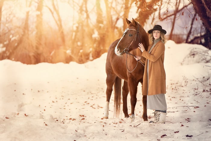 Woman in hat with horse in winter forest