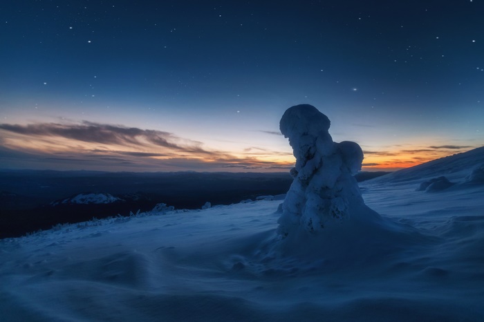 Snow-covered rock formation under starry night sky