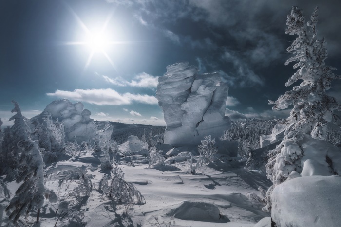 Snowy mountain landscape with sun and rock formations