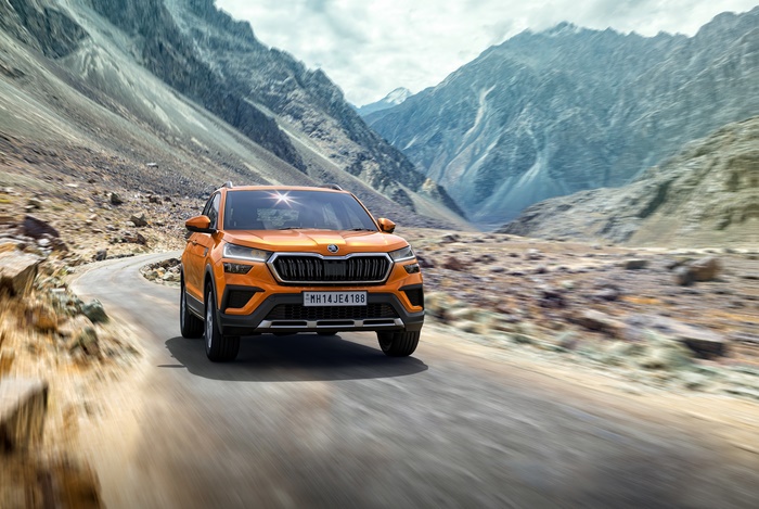 Orange Škoda Kushaq SUV driving on a mountain road