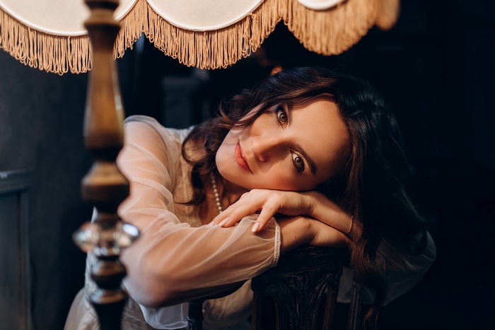 Woman with brunette hair leaning on a chair