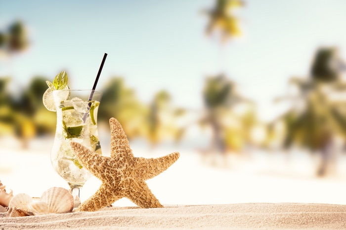 Mojito cocktail with starfish and shells on sand