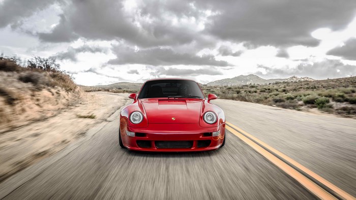 Red Porsche 911 driving on a desert road