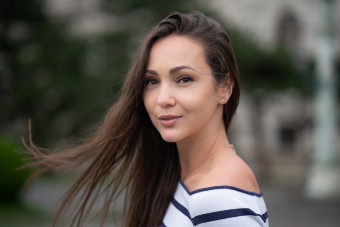 Woman with long brown hair and off-the-shoulder top